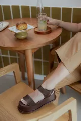 Sandalias de plataforma color marrón oscuro con textura de reptil en la tira frontal y el talón. Cuentan con cierre de velcro lateral y suela de plataforma forrada.