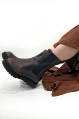 Bota de cuero color marrón chocolate, con elásticos laterales negros, cierre lateral y suela track color negro.