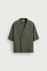 Camisa relaxed fit verde militar confeccionada en tejido fluido con mezcla de viscosa y lino, cuello con solapas de muesca, manga corta y cierre frontal de botonadura cruzada.