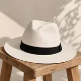 Sombrero de paja color blanco con cinta negra alrededor de la copa, de ala mediana y diseño clásico.