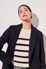 Blazer negro de corte clásico con solapas y mangas largas con puños con rayas verticales.