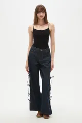 Pantalon de jean azul oscuro de corte ancho y tiro bajo, con detalle de aberturas laterales ajustables mediante lazos.