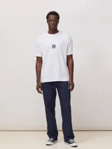 Camiseta blanca de corte oversize, confeccionada en algodón orgánico de alto gramaje. Presenta un diseño gráfico estampado en el centro del pecho con el logo de la marca.