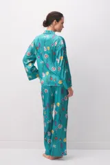Pijama de satén turquesa con estampado floral multicolor, compuesto por una camisa de manga larga con botones y cuello camisero, y pantalón largo a juego.