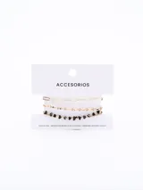 Set de tres brazaletes dorados con diferentes diseños: uno de cadena de eslabones ovalados, uno de cadena fina con pequeñas esferas y uno de cadena con dijes de corazones negros.