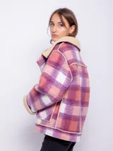 Tapado corto con diseño a cuadros en tonos violeta, rosa y blanco. Cuenta con interior de corderito color beige y cierre frontal con cremallera diagonal.