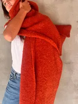 Chal de punto bouclé color marrón claro, hecho de 100% baby alpaca. Tejido suave, esponjoso y cálido, ofrece una textura envolvente y lujosa.