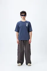 Remera negra de corte amplio con mangas cortas y cuello redondo. Presenta un pequeño estampado rectangular en el pecho y un estampado grande en la espalda con motivos japoneses.