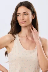 Musculosa de algodón blanca con pequeño estampado floral y volados en los tirantes, de corte clásico.