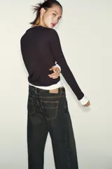 Camiseta de manga larga color gris melange, con cuello redondo y bajo recto. Presenta un detalle de tejido efecto doble a contraste en el cuello, puños y dobladillo inferior en color blanco.