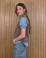 Chaleco marrón de denim con pespuntes en contraste, cuello redondo y cierre frontal con botones.