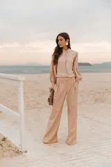 Camisa color beige de corte clásico, con cuello camisero, mangas largas abullonadas y cierre frontal con botones.