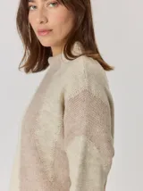 Buzo de tejido de punto con diseño de rayas verticales anchas en tonos beige y crema, cuello semipolera y manga larga.