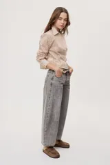 Camisa de manga larga con diseño de rayas verticales en tonos celestes, blancos y marrones, confeccionada en tejido semitransparente con cuello camisero y cierre frontal de botones.