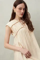 Vestido largo color salmón con estampado abstracto, escote con lazo y mangas cortas. Diseño fluido con frunces en el pecho.