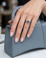 Anillo de plata 925 con diseño de tres piedras, presentando una circonia azul central de corte ovalado rodeada por un halo de pequeñas circonias blancas, flanqueada por dos circonias azules laterales más pequeñas.