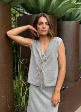 Chaleco blanco tejido en lino con escote en V y cierre frontal con lazos.