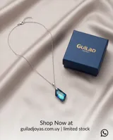 Collar de plata con cadena fina y dije de cristal facetado en forma de gota con tonalidades azul y violeta.