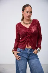 Blusa de encaje color bordó, de manga larga, con escote en V y volados en el borde delantero.