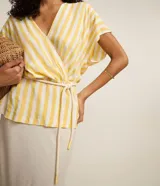 Blusa de viscolino a rayas verticales azul marino y blanco, con escote en V cruzado, mangas cortas y cinturón de cuerda en la cintura.