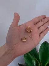 Ear cuff de diseño minimalista y forma esférica, acabado en tono dorado brillante.