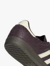 Championes Adidas Samba OG de caña baja, con diseño clásico de puntera en forma de T y tres bandas laterales dentadas. Presenta un empeine de cuero con estampado texturizado en color bordó y detalles en crema, sobre una suela de goma oscura.