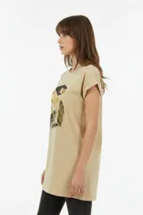 Remera de algodón blanca, de corte holgado, manga corta con vuelta y cuello redondo. Cuenta con un estampado frontal abstracto con trazos en tonos marrón y foil dorado.