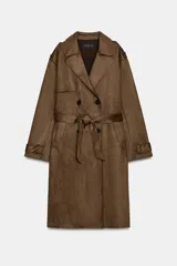 Trench largo de color marrón con efecto ante, cuello con solapa, cierre frontal cruzado con botones y cinturón ajustable del mismo tejido. Cuenta con bolsillos delanteros de vivo y mangas largas con trabillas en los puños.