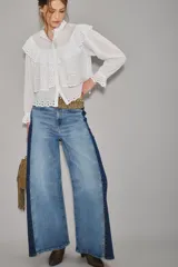 Jean de corte wide leg con diseño bicolor, presentando un panel central en denim lavado claro y paneles laterales en denim azul oscuro. Posee tiro alto y cierre frontal con botón.