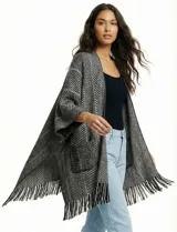 Cardigan tipo kimono de tejido suave, color negro y blanco con patrón de espiga (herringbone). Presenta bolsillos delanteros y terminación con flecos en el ruedo.