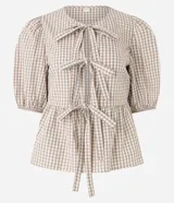 Blusa de tricolina de algodón con estampado de cuadros vichy, mangas cortas abullonadas, cuello redondo, abertura delantera con lazos y recorte fruncido en la cintura.