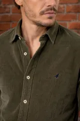 Camisa de pana color verde militar, corte slim fit, con cuello camisero, cierre frontal con botones claros y pequeño bordado de un pájaro en el pecho.