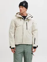 Campera técnica impermeable y cortaviento con capucha ajustable, diseñada para condiciones de frío y nieve. Cuenta con cierre frontal, bolsillos con cierre, ventilación bajo los brazos y ajustes en puños.