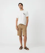 Bermuda de sarga color beige, de corte recto y estilo clásico. Cuenta con bolsillos laterales y traseros, cierre frontal con botón y bragueta.