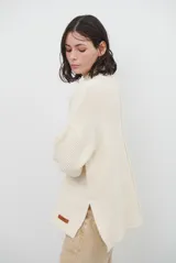 Polera de tejido de punto color chocolate, con cuello alto, mangas largas con puños acanalados y detalle de costura central vertical. Incluye una pequeña etiqueta de cuero sintético en el ruedo.