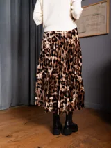 Pollera midi plisada de terciopelo con estampado animal print. Presenta un corte acampanado y fluido.