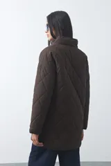 Campera capitoneada de largo medio, color negro, con cuello alto, cierre frontal con cremallera y broches a presión, y bolsillos laterales con solapa.