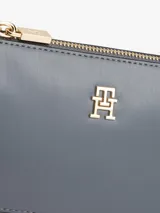 Cartera tipo baguette de Tommy Hilfiger con acabado liso, cierre de cremallera y correa de cadena metálica dorada. Presenta el monograma TH en la parte frontal.