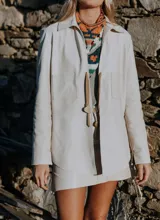 Campera de cuero color beige claro, estilo sobrecamisa o chaqueta ligera, con cuello camisero, cierre frontal con broches de nácar y dos bolsillos de parche en el pecho.