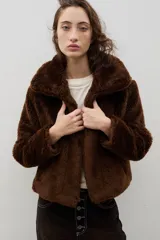 Campera corta de piel sintética en color crema, con cuello amplio tipo solapa y cierre frontal.