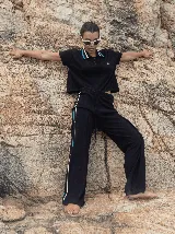 Pantalón de punto color negro, de corte holgado y pierna ancha, con pretina elástica y cordón de ajuste. Presenta rayas laterales en color blanco y azul.