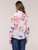 Camisa de gasa blanca con estampado floral multicolor, cuello con solapa, mangas largas y cierre frontal con botones. Cuenta con terminación delantera anudada y espalda más larga.