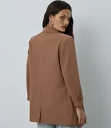Blazer de sastrería color bordó, de corte oversized y largo, confeccionado en crepé. Presenta solapas clásicas, bolsillos frontales y detalle de pliegues en los puños.