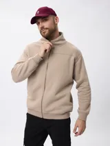 Campera de felpa color beige con cierre frontal completo, cuello alto y puños y ruedo acanalados.