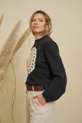 Buzo de punto color negro con cuello redondo, mangas largas y detalle de mandala tejido en color crema en el frente.