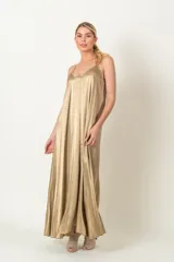 Vestido largo y amplio de satén color dorado, con escote en V y tirantes finos.