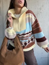 Sweater de tejido de punto con diseño a rayas horizontales y motivos geométricos, cuello alto con cierre frontal parcial, mangas largas abullonadas y puños acanalados.