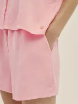 Shorts cortos color blanco de lino y lyocell, con bolsillos laterales, pretina con elástico y terminaciones en cobre.