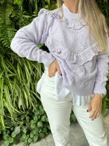 Sweater lila de punto calado con volados en el cuello, el pecho y los puños.