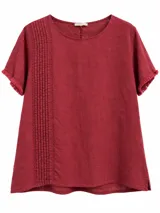 Blusa de lino color bordó, con cuello redondo, manga corta y detalles de alforzas y bordados verticales en el frente, además de flecos en las terminaciones de las mangas.